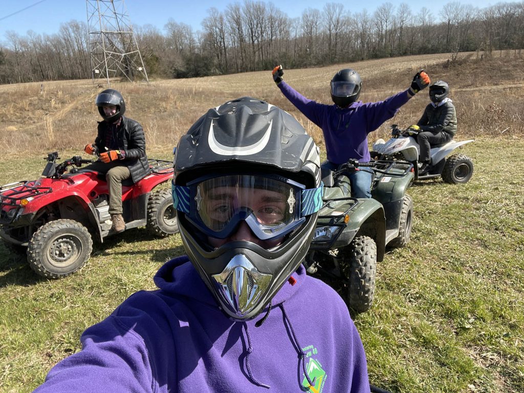 4 members of a Venturing Crew find Adventure by riding all terrain vehicles in an open field